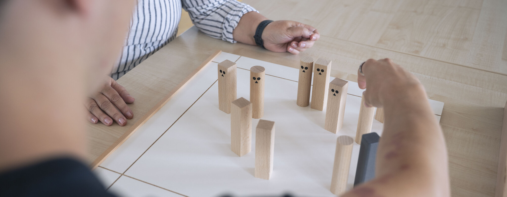 Close-Up von zwei Handpaaren beim Rollenspiel mit bemalten Holzkl&ouml;tzen