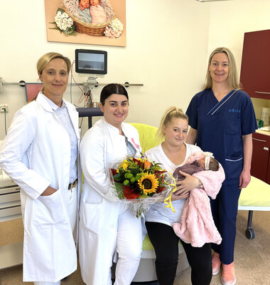 Die glückliche Mutter mit Baby und dem Team des Kreißsaals