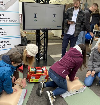 Studierende leiten Besucher zur Reanimation an speziellen Übungspuppen an