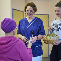 Pflegekr&auml;fte &uuml;bergeben ein Geschenk an eine Patientin