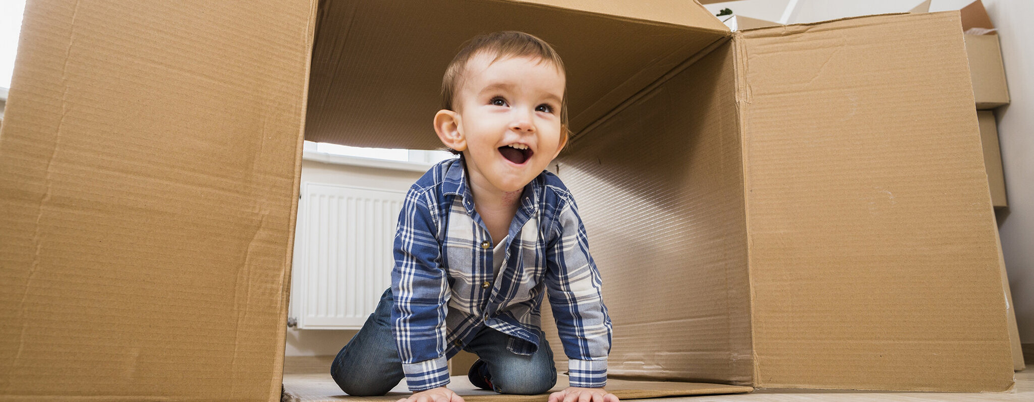 Kleiner Junge krabbelt aus Pappkarton heraus